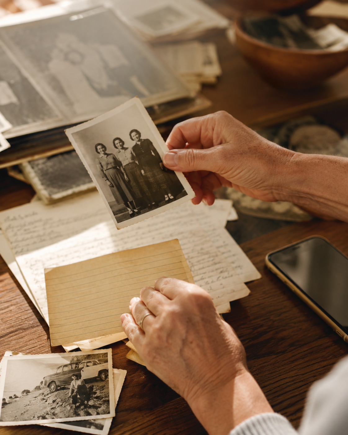 Hands organizing old family photos on a table.